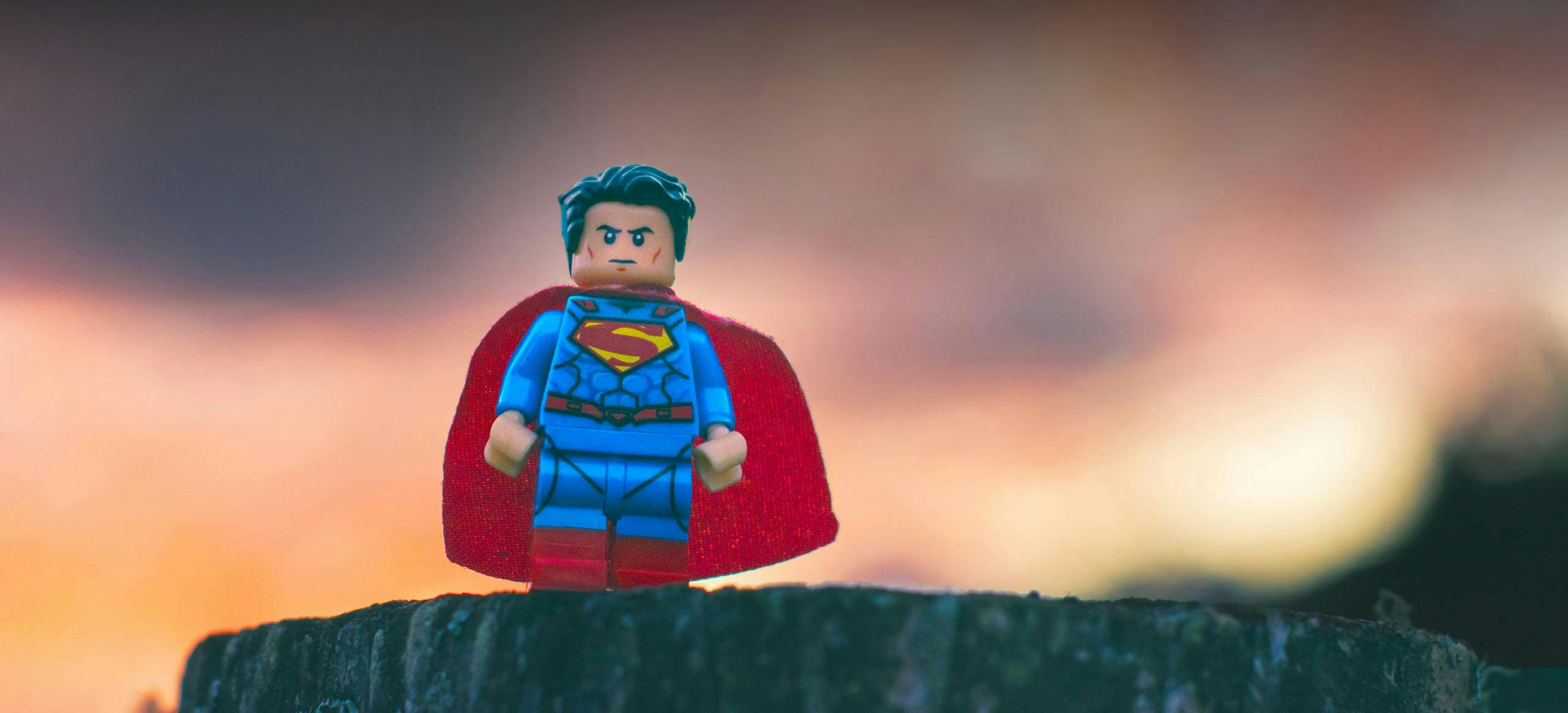 A lego superman figure standing on a rock